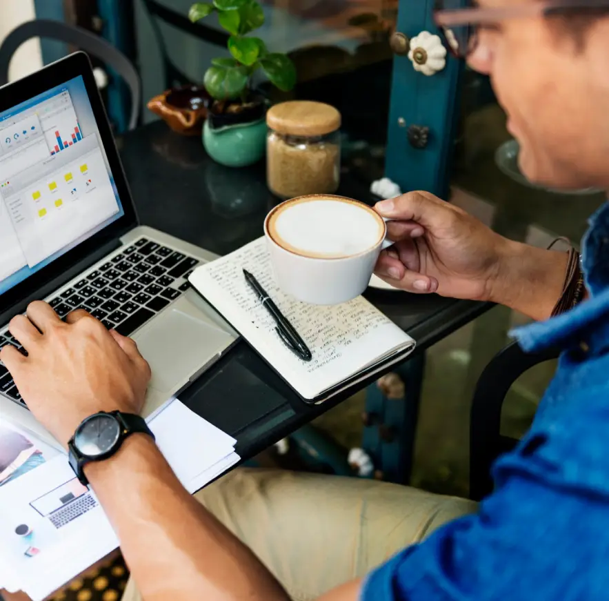 Man reviewing digital analytics on a laptop in a cafe, exemplifying the detailed approach to achieving proven results in digital marketing for clients in Kochi.