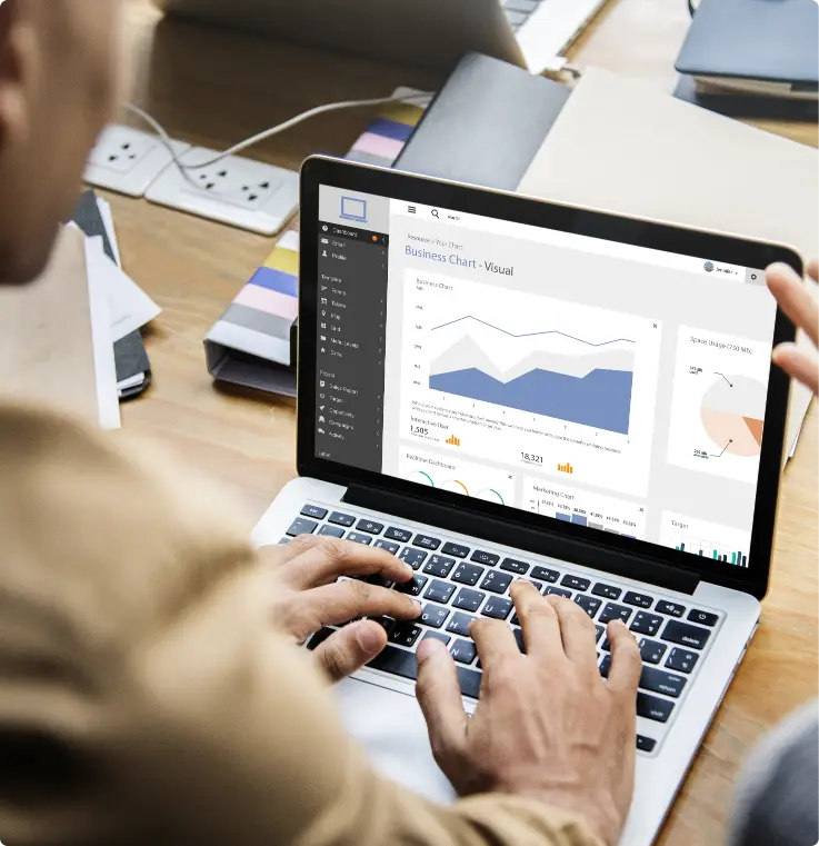 A person working on a laptop displaying a business chart, next to a list highlighting the benefits of social media in engaging the target audience, including increased visibility, enhanced customer interaction, cost-effective marketing, driving conversions, and building brand trust.