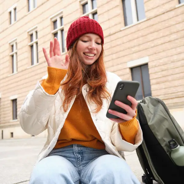 Woman in a red beanie using her smartphone, illustrating TechPullers' tailored web solutions for Buy Canadian SIM, simplifying mobile service accessibility for students and newcomers to Canada.