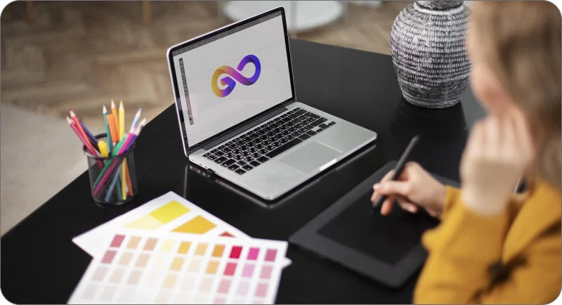 Techpullers web design services in Kerala, designer using laptop and tablet with color palettes and branding logo design, highlighting unique approach to website development